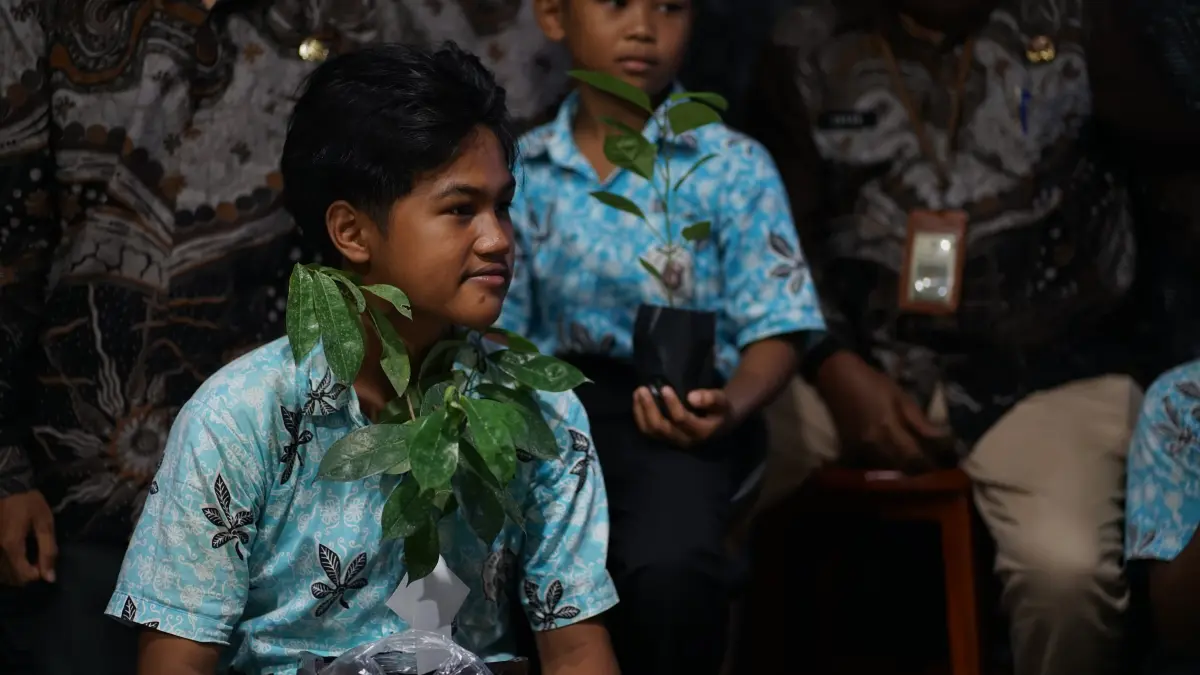 CINTA LINGKUNGAN: Kepala SDN Selolembu Catur Mega Sofianto (tengah) bersama muridnya menunjukan bibit pohon yang berasal dari limbah MBG.(ILHAM WAHYUDI/RADAR IJEN)