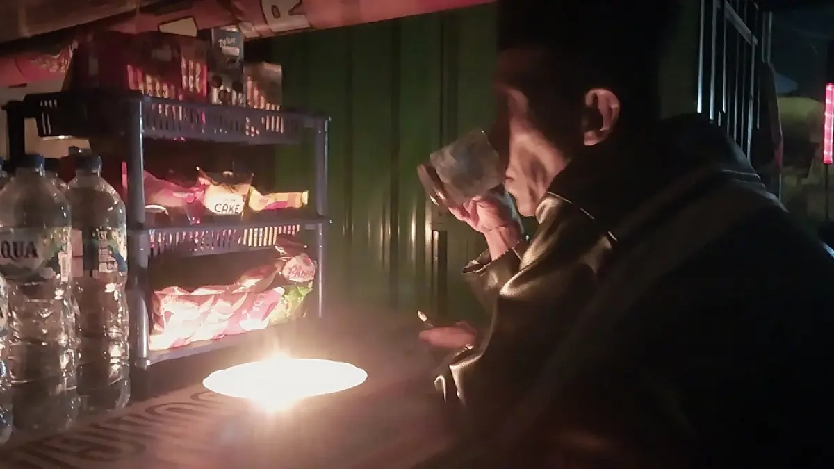 NYALAKAN LILIN: Wahyu, pemilik warung di Dusun Curahbuntu, Desa/Kecamatan Jenggawah, terpaksa menyalakan lilin saat terjadi pemadaman listrik pada Rabu (10/6) malam. (JUMAI/RADAR JEMBER)