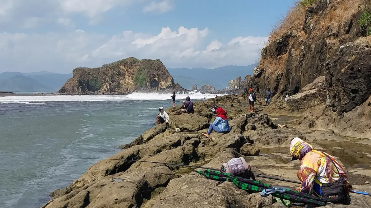 JADI SPOT MANCING: Pemancing memanfaatkan spot timur Bukit Seroyo (Teluk Love) untuk memancing, di Dusun Watu Ulo, Desa Sumberejo, Kecamatan Ambulu, Minggu (20/6).(JUMAI/RADAR JEMBER)