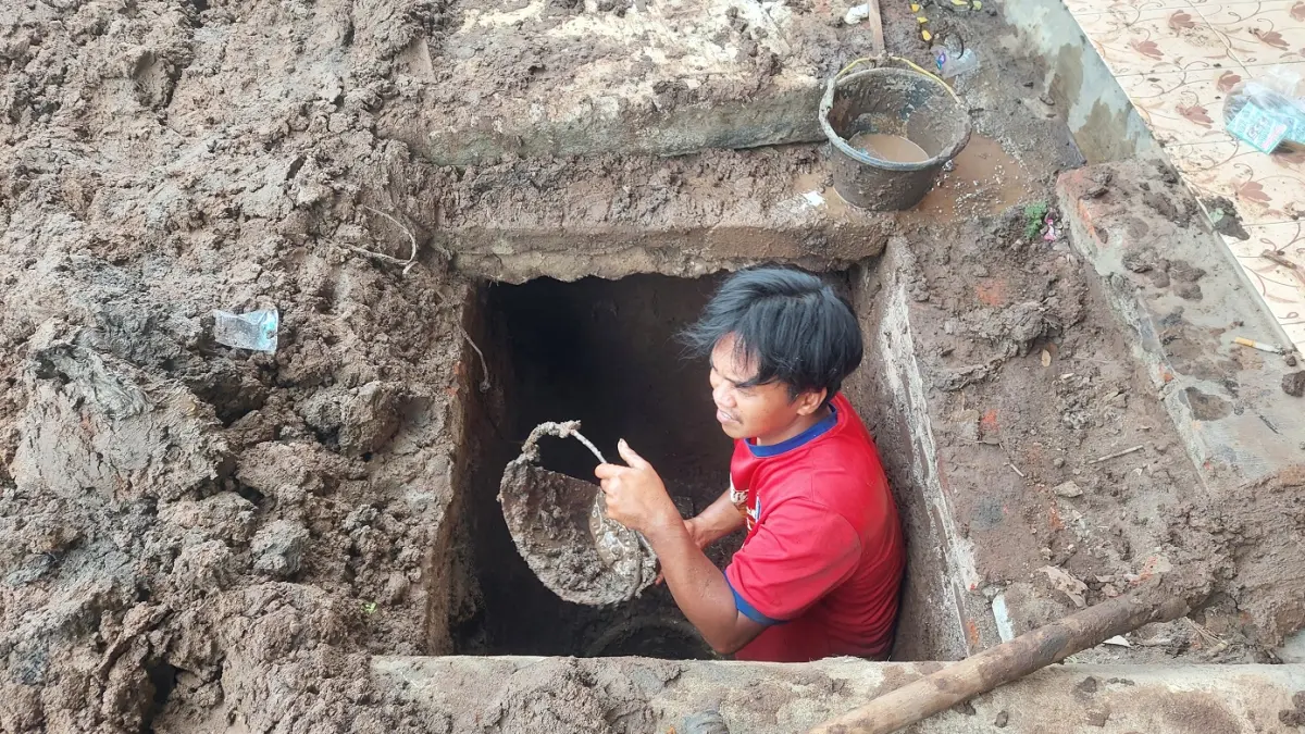 ENDAPAN: Petugas membersihkan lumpur di saluran drainase Jalan Mastrip. Saat hujan deras tiba jalan di kawasan kampus itu kerap banjir, salah satu penyebabnya adalah penyempitan saluran drainase. (DWI SISWANTO/RADAR JEMBER)