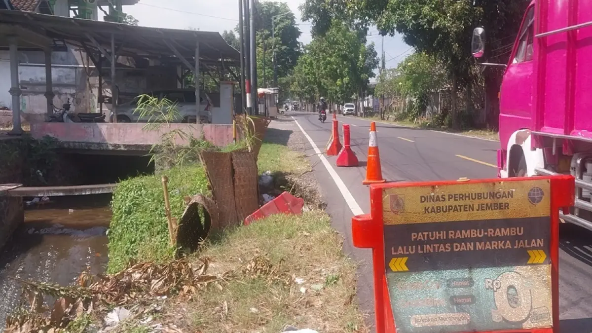 BELUM DIPERBAIKI: Kondisi plengsengan ambrol di ruas Jalan Nasional Jember–Banyuwangi, Dusun Dam Sola, Desa Tegalrejo, Kecamatan Mayang, yang hingga kini belum mendapatkan perbaikan permanen meski kerusakan terjadi sejak akhir Maret lalu.(JUMAI/RADAR JEMBER)