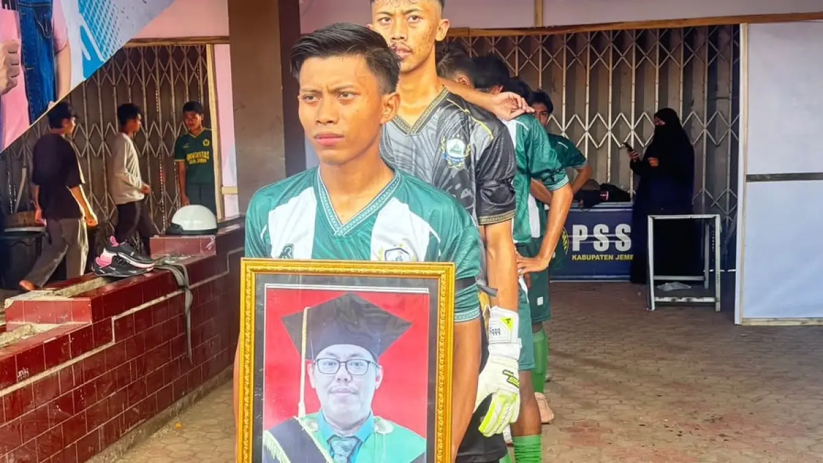 PENGHORMATAN: Pemain Tim Sepak Bola UIN KHAS mengenakan pita hitam di lengan membawa foto almarhum rektor Prof Hepni sebelum pertandingan Liga Mahasiswa 2026 di Stadion Notohadinegoro, Kelurahan Jembelor, Kecamatan Patrang, Minggu (21/6). (ROFIQ)