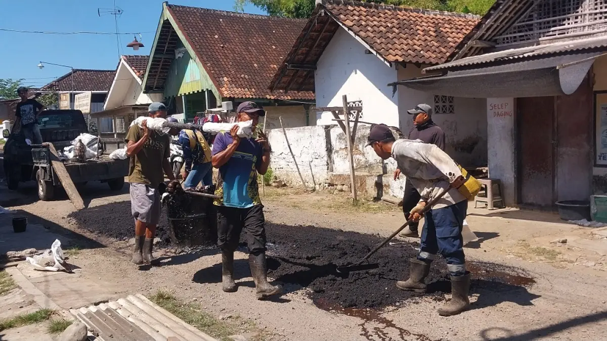 PERAWATAN: Petugas dari Dinas Bina Marga Kabupaten Jember melakukan perawatan jalan di Dusun Krajan, Desa/Kecamatan Ambulu, Rabu (1/7). (JUMAI/RADAR JEMBER)
