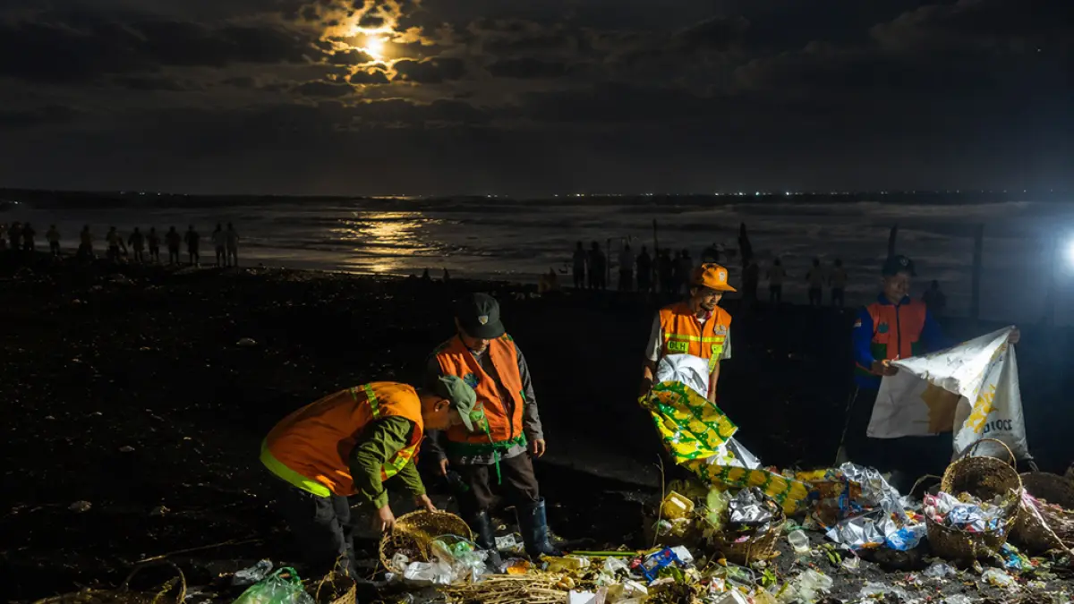 TANGANI: Petugas kebersihan Dinas Lingkungan Hidup (DLH) Lumajang saat mengumpulkan sampah di pantai Watu Pecak, Pasirian, Lumajang. (KOMINFO FOR RAME)