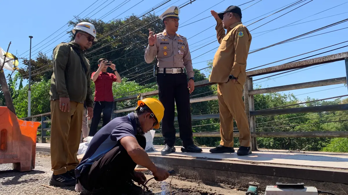 DIPANTAU: Wakil Bupati Bondowoso, As’ad Yahya Syafi’i (kanan) bersama Kasat Lantas Polres Bondowoso, AKP Irwan Rizky Prakoso (kiri) melihat petugas yang tengah melakukan perbaikan. (ILHAM/RADAR IJEN)