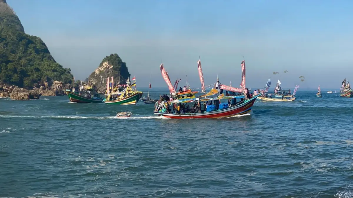 SEMARAK: Sejumlah kapal nelayan saat melintasi pelawangan Pancer Puger untuk membawa sesaji berisi hasil bumi untuk dilarung di tengah laut, dalam rangkaian acara Petik Laut di Pancer Puger, (30/6). (DISKOMINFO JEMBER)