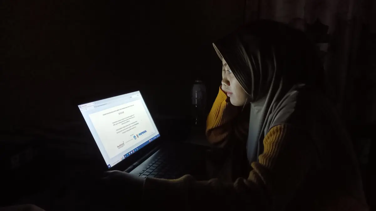 FOKUS: Fatimah Azzahra Guru Honorer di salah satu MI di Kecamatan Tempurejo rela lembur menuntaskan pekerjaannya di sekolah karena akses wifi. (M. ASHI SURYA/RADAR JEMBER)