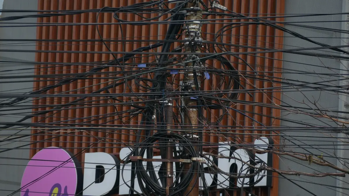 RUWET: Kondisi kabel yang banyak ditemui terpasang tanpa beraturan di tiang-tiang di jalanan Jember. Salah satunya di kawasan Kecamatan Kaliwates. (SIDKIN ALI/RADAR JEMBER)