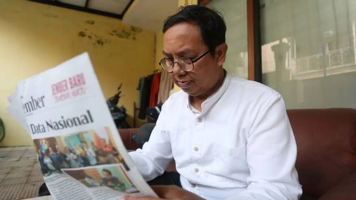 MEMBACA SAMPAI SENJA: Anang Hudijono pelanggan Jawa Pos Radar Jember yang masih membiasakan membaca koran setiap pagi seperti masa mudanya dulu. (SIDKIN ALI/RADAR JEMBER)