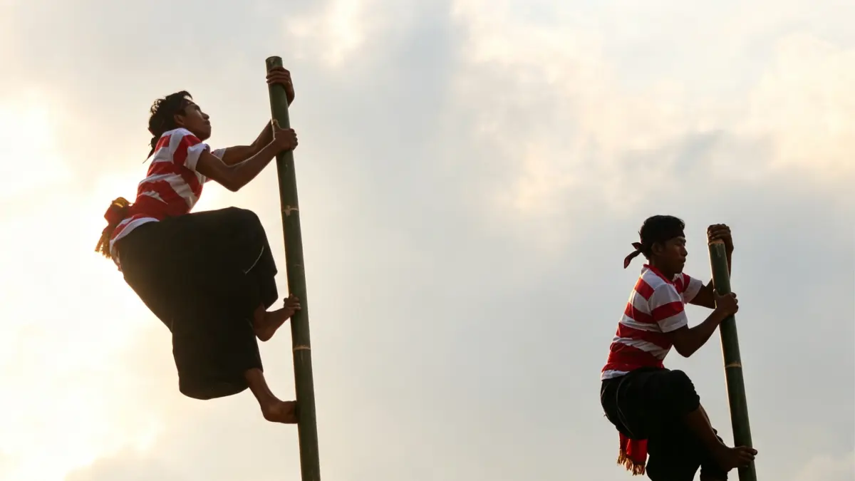 EKSTRIM: Warga menaiki bambu untuk memperagakan beberapa gerakan, sebagai salah satu ritual dalam Tradisi Pojhien yang biasa dilakukan di Desa Karanganyar, Kecamatan Klabang. (ILHAM/RJ)