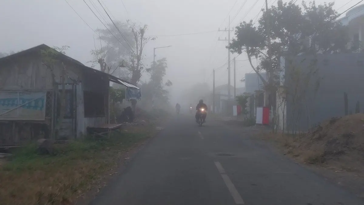MULAI BERKABUT: Pengendara sepeda motor melintas di ruas jalan yang mulai diselimuti kabut pada pagi hari, kemarin pagi (3/8). Pengguna jalan diimbau meningkatkan kewaspadaan karena jarak pandang berkurang. (JUMAI/RADAR JEMBER)