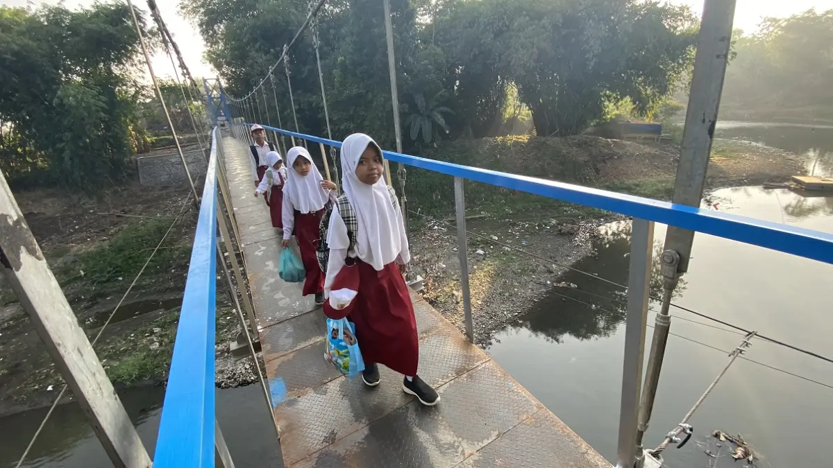 PENGHUBUNG: Sejumlah pelajar melintasi jembatan gantung di Desa Jubung. Anak-anak sekolah pun semakin berani berangkat sendiri ke sekolah, walau jembatan gantung belum tuntas seratus persen. (JUMAI/RADAR JEMBER)