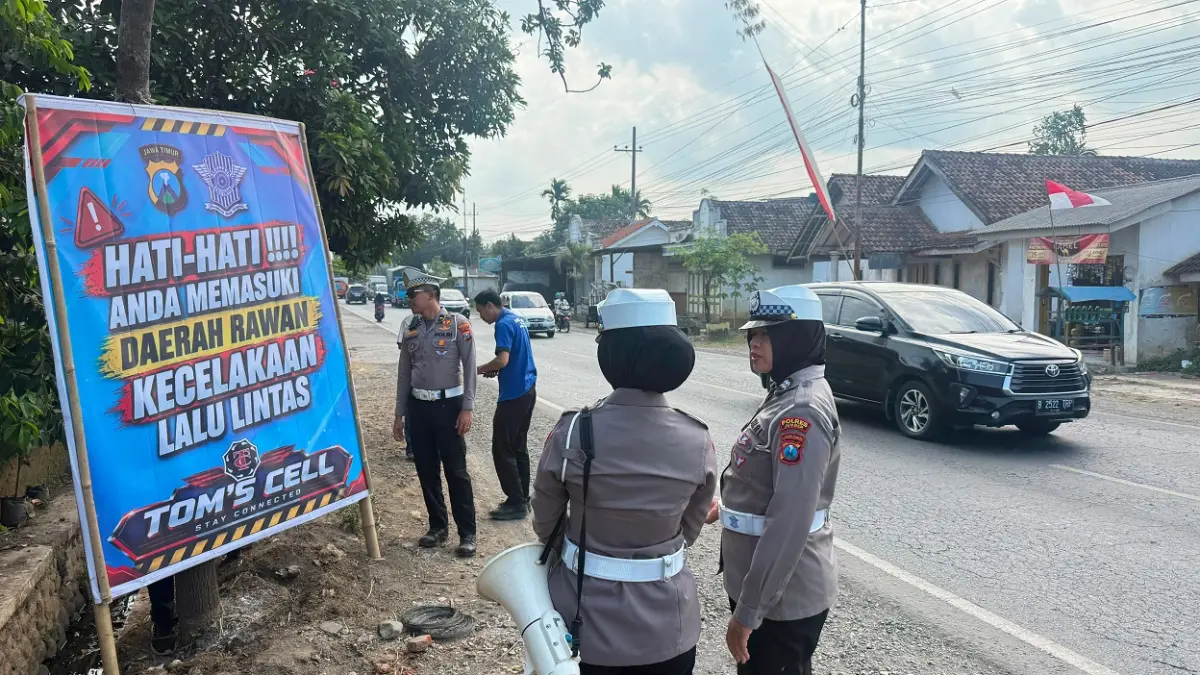 BERI IMBAUAN: Satlantas Polres Jember memasang banner peringatan di jalur rawan kecelakaan di Desa Langkap, Kecamatan Bangsalsari, kemarin (5/8). (JUMAI/RADAR JEMBER)