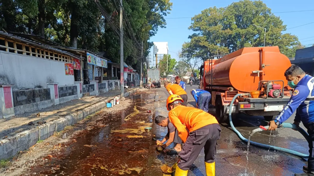 BERSIHKAN JALAN: Petugas Damkar bersama personel BPBD Jember saat membersihkan ceceran tetes tebu di Jalan Brawijaya, Desa Jubung, Kecamatan Sukorambi, Rabu (12/8). (BPBD Jember)