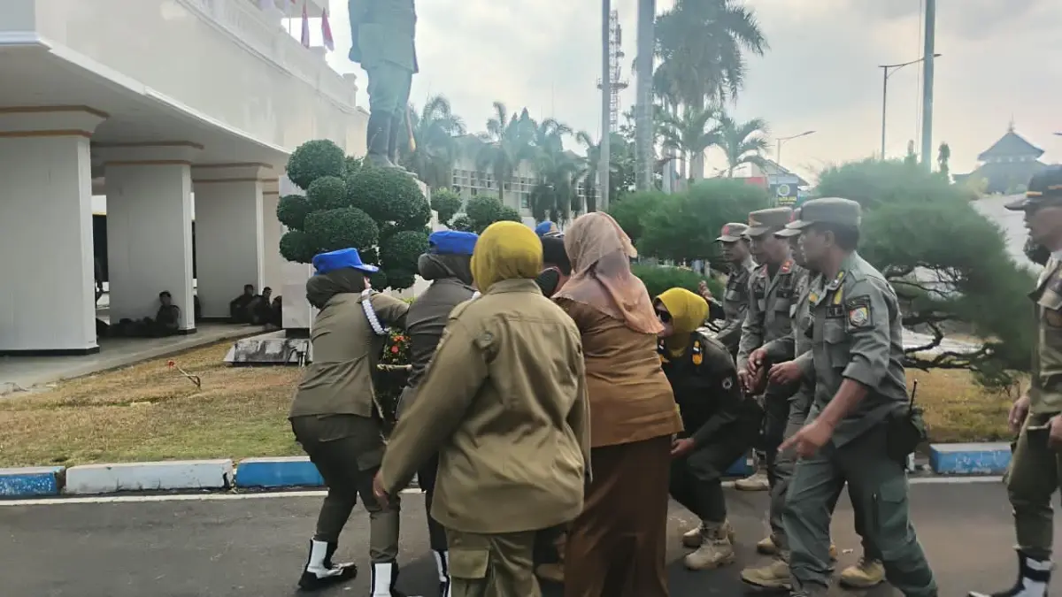 DI BAWAH TERIK: Kepala Diskopumdag Jember, Sartini pingsan dan dibopong Satpol PP ke lobi Kantor Pemkab Jember, kemarin (15/9). (SIDKIN ALI/RADAR JEMBER)