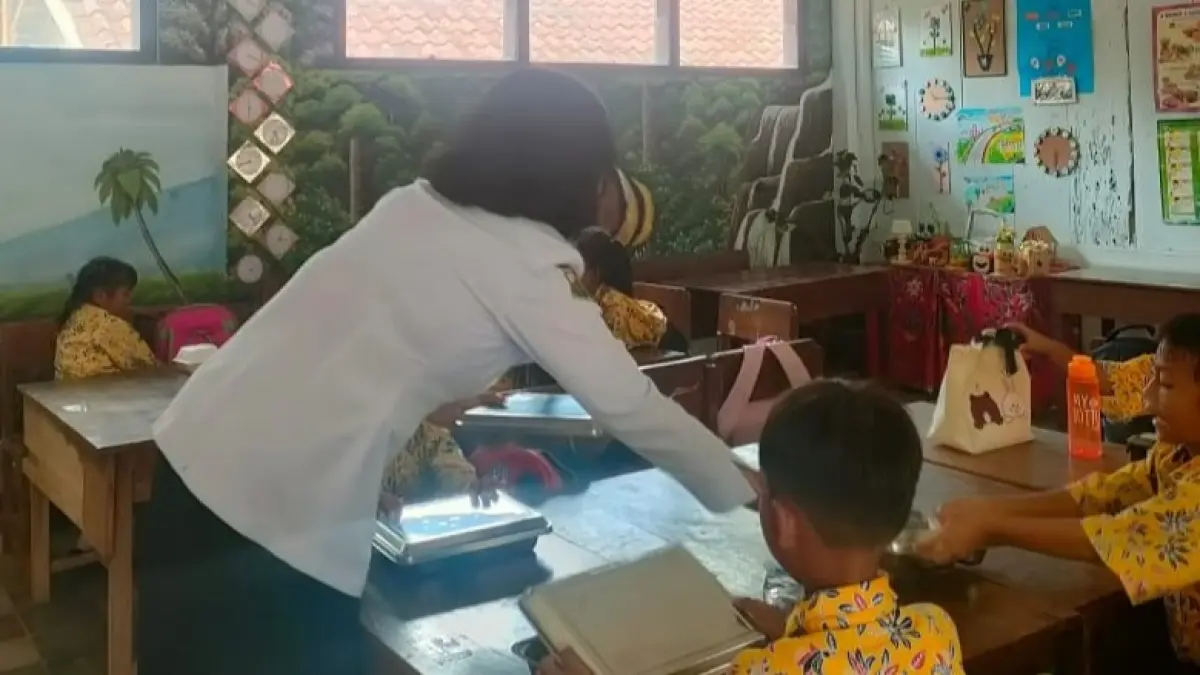 DIBAGIKAN: Seorang guru saat membagikan MBG kepada para siswa. (FAQIH HUMAINI/RADAR IJEN)