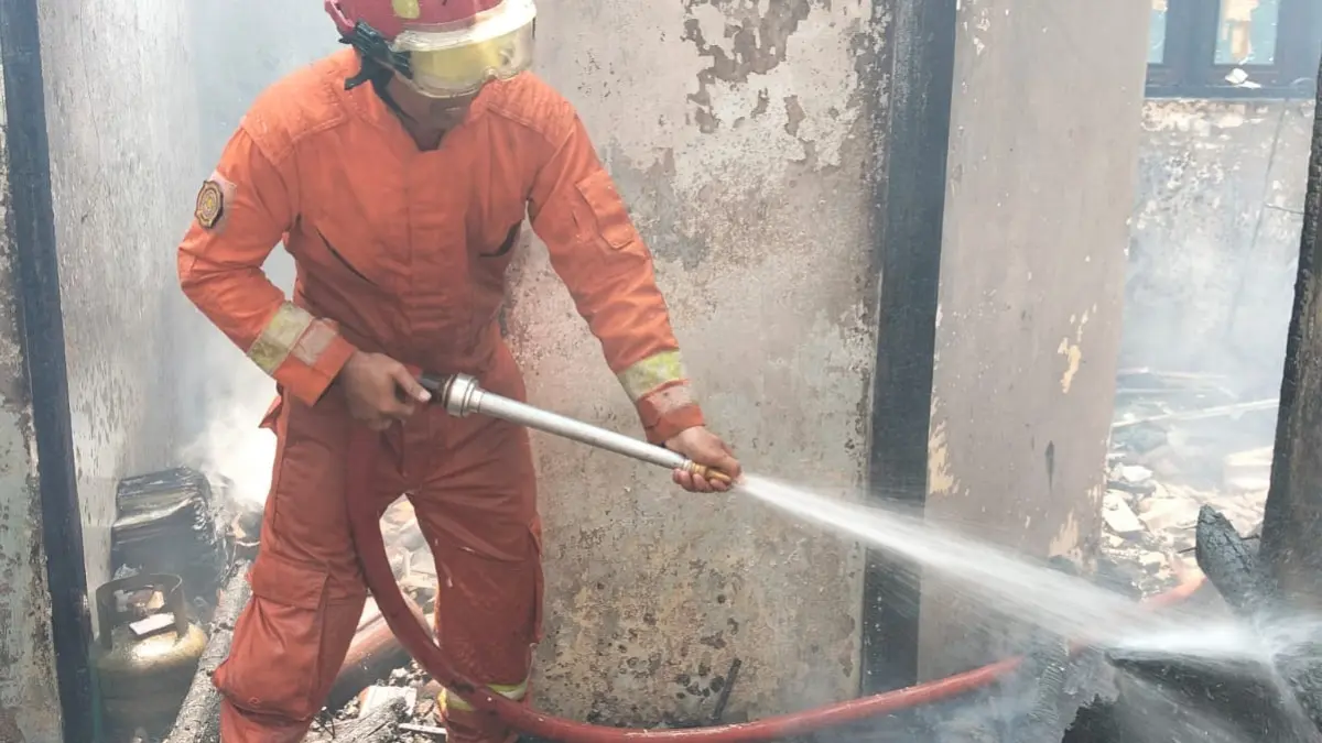 LAKUKAN PENDINGINAN: Petugas pemadam kebakaran dari Posko Ambulu melakukan pendinginan di rumah milik Jamina, wargaDesa Cangkring, Kecamatan Jenggawah, yang terbakar pada Senin (12/10) pagi. Kebakaran diduga akibat korsleting listrik saat rumah dalam kondisi kosong dan terkunci. (DAMKAR JEMBER)