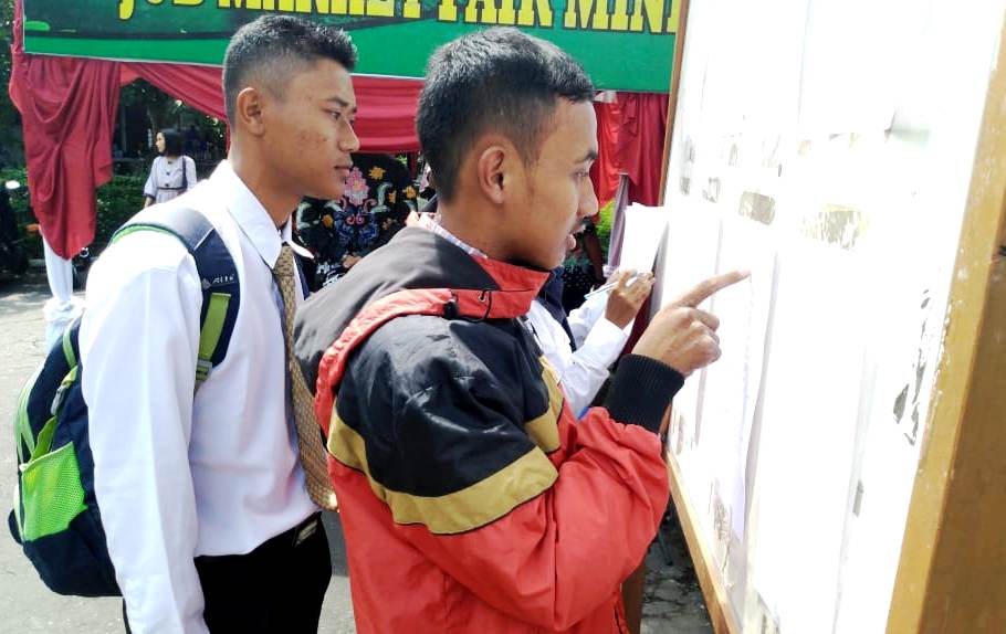 MEMBURU PEKERJAAN: Para pelamar terlihat antusias mencari lowongan kerja sesuai yang diinginkan di acara job fair di halaman Disnaker Lumajang.