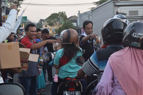 BERSEDEKAH: Para anggota Paguyuban Travel Jember (PTJ) membagikan takjil di depan kantor Radar Jember