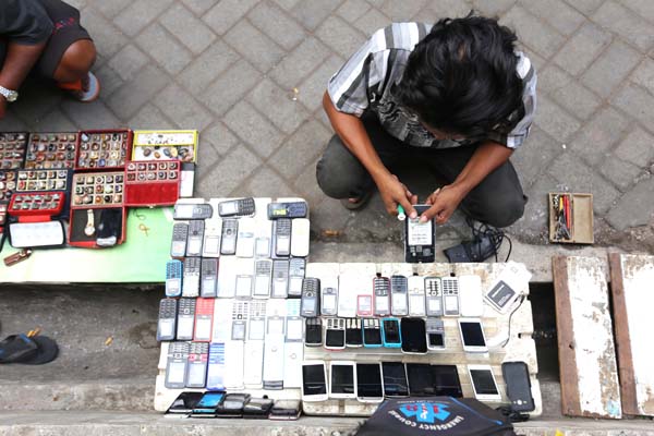 BARANG BEKAS: Agus Stiawan dan dagangan casing HP di Pasar Loak, Kepatihan, Kaliwates.