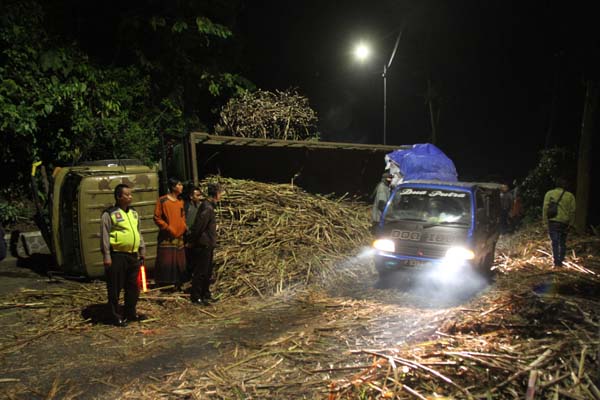 BIKIN MACET: Truk gandeng penuh muatan tebu terguling di jalan menikung dan menurun sehingga menyebabkan jalan di jalur Gumitir macet total.