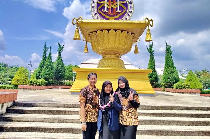 BANGGA: Okta Diana Anggrayni (tengah) berpose di depan gedung utama Walailak University International College (WUIC) Thailand, Kamis (14/11). (VOLUNTER BIPA FOR RadarMadura.id)