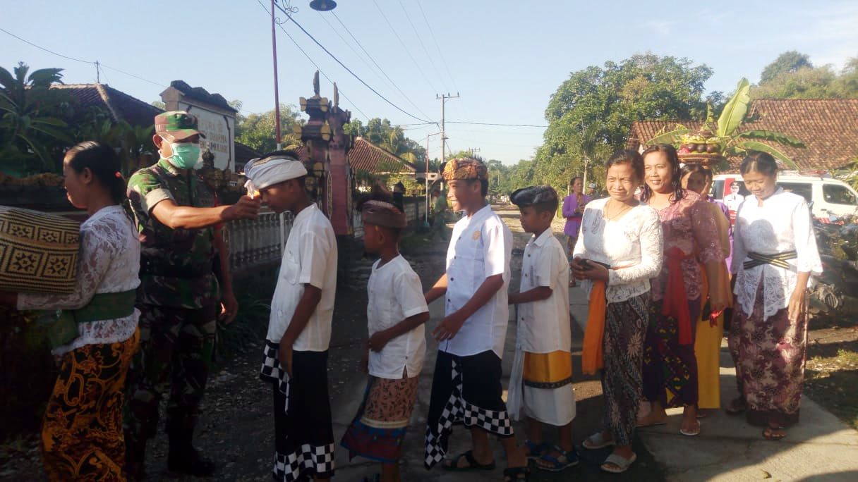 CEK SUHU TUBUH: Umat Hindu yang datang ke Pura Swasty Dharma di Desa Sukoreno, Umbulsari, harus melewati petugas yang mengecek suhu tubuh, kemarin (26/03).