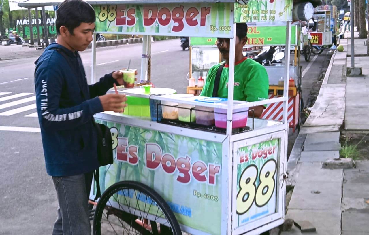 TERUS NAIK: Salah seorang warga baru saja membeli es doger di kawasan Alun-Alun Jember. Dampak naiknya harga gula membuat pedagang es pusing. Sebab, mereka tidak berani menggunakan pemanis buatan yang harganya lebih murah.