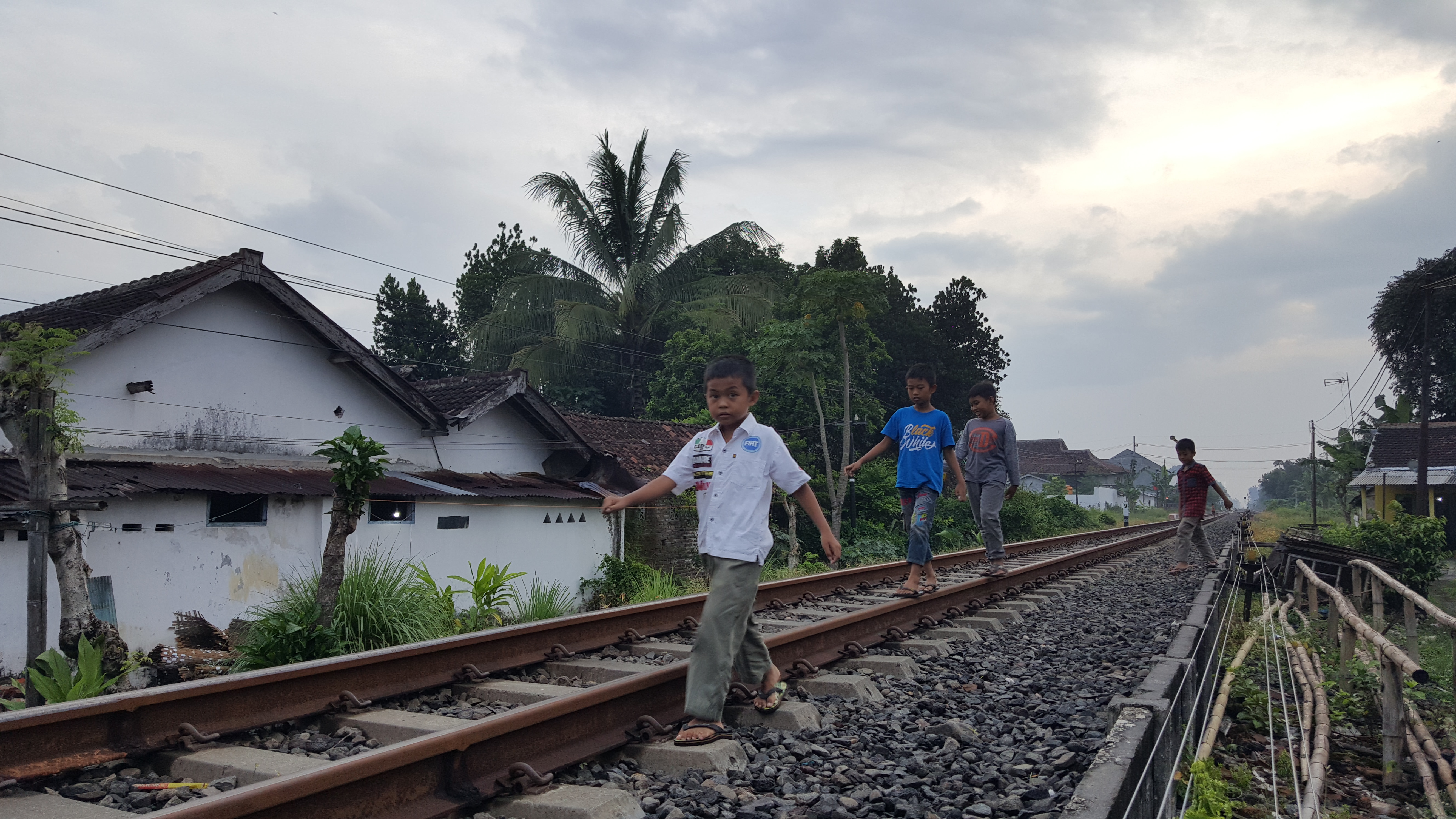MENIKMATI SENJA: Beberapa anak bermain di pinggiran rel KA di sekitar Stasiun Mangli, Kecamatan Kaliwates. Mereka bermain sembari menunggu waktu Magrib tiba.