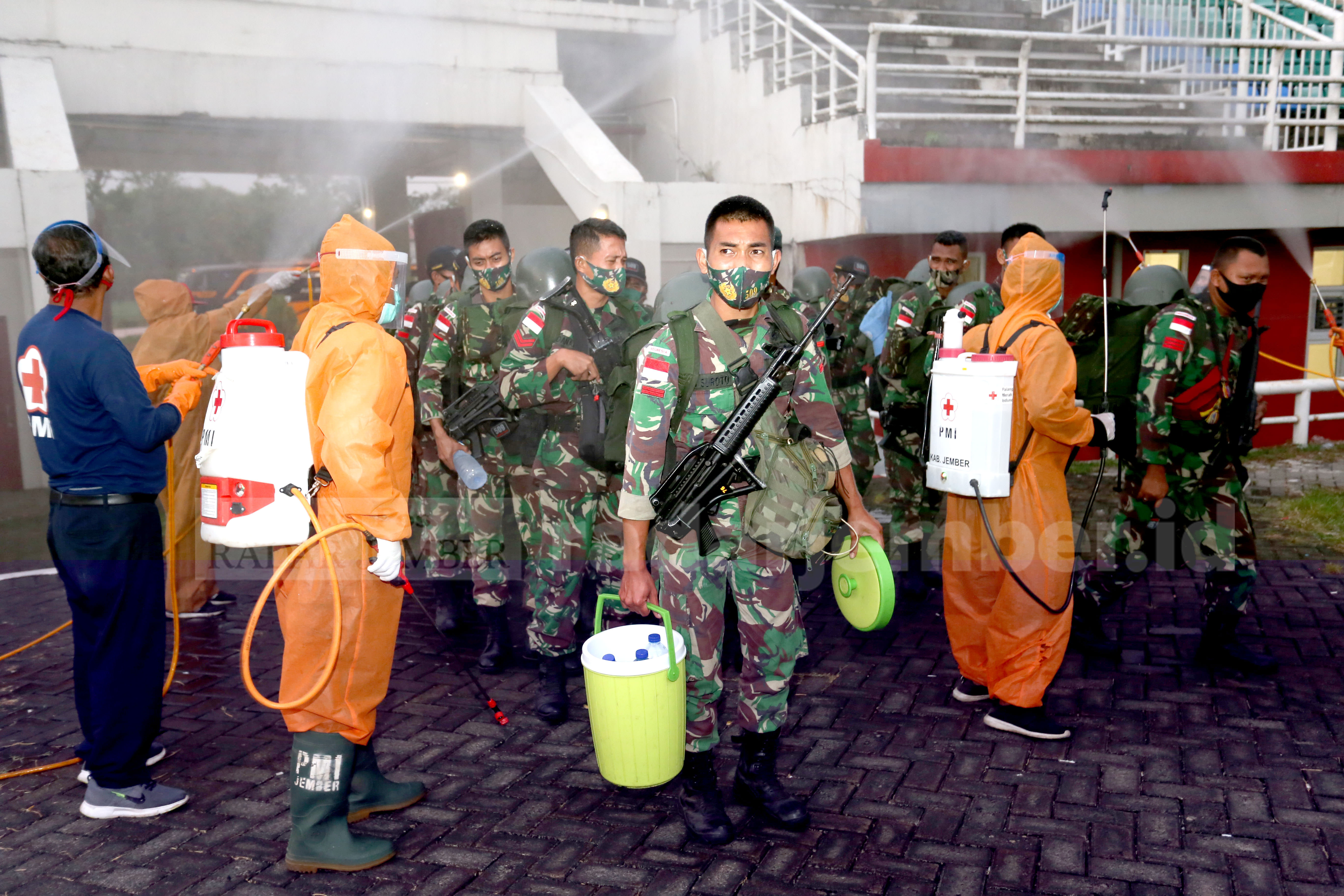 LANGSUNG DIKARANTINA: PMI Jember menyemprotkan cairan disinfektan kepada anggota Yonif Raider 509/Kostrad, kemarin (25/8). Ratusan anggota TNI ini akan diisolasi usai bertugas dari Pamtas RI-PNG.
