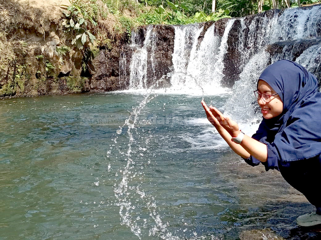BERSIH DAN JERNIH: Salah satu pengunjung bermain air sembari menikmati keindahan Air Terjun Sumber Salak, di Ledokombo.