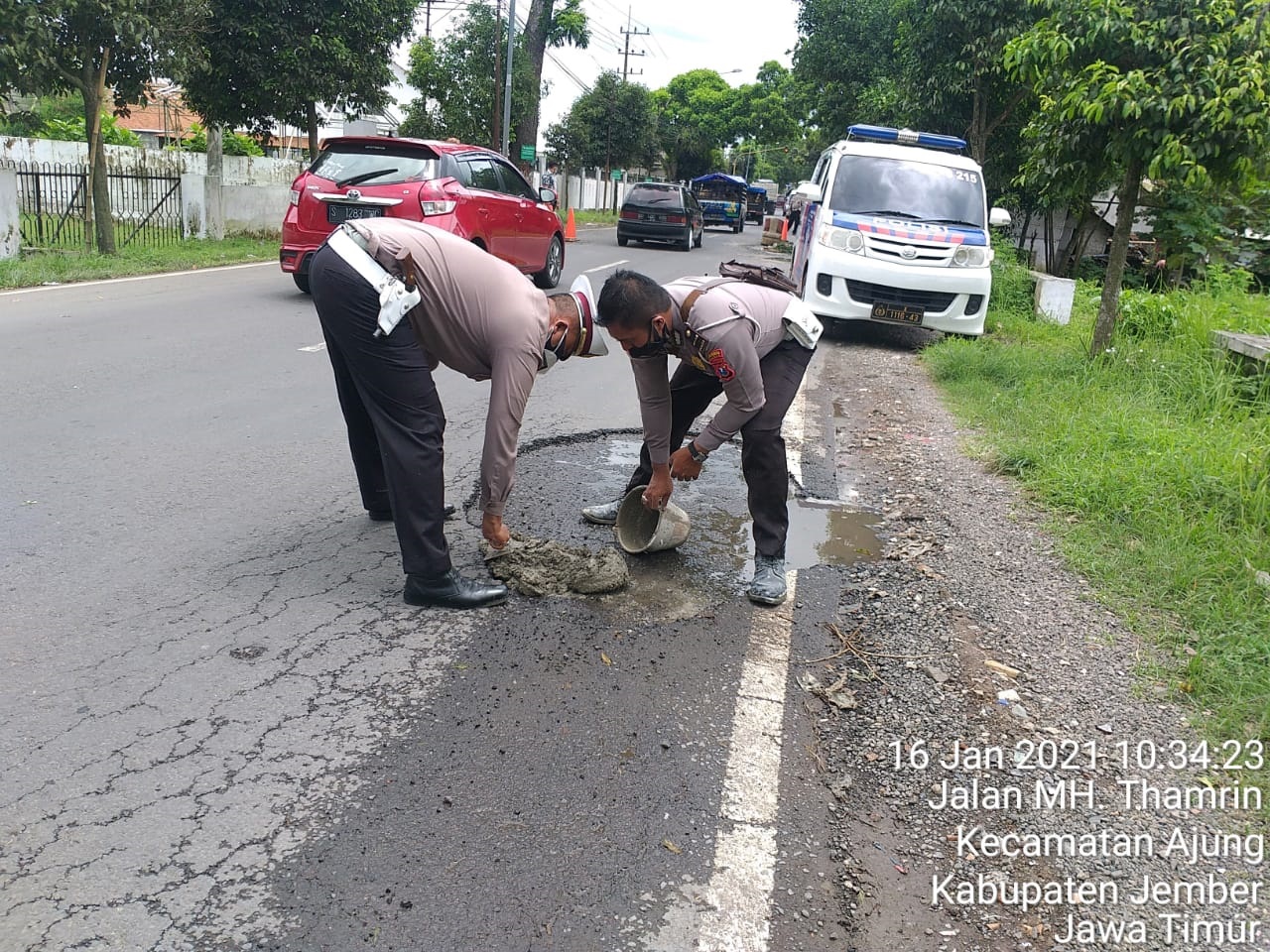 DITUTUP SEMEN: Anggota Polres Jember mulai menambal jalan berlubang dengan semen di Jalan MH Thamrin, Ajung. Penambalan dengan semen tersebut menjadi langkah pencegahan kecelakaan, meski hanya bersifat sementara.