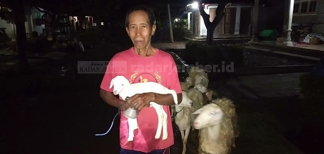 SAYANG TERNAK: Asmo, salah seorang warga Wonoasri terdampak banjir sampai menggendong kambing miliknya. Pria 65 tahun ini akan membawa ternaknya tersebut ke tempat aman.