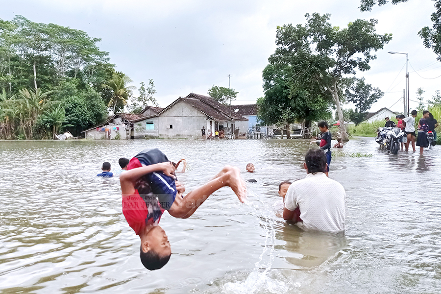 SALTO: Anak-anak Desa Darungan, Yosowilangun, memanfaatkan sawah yang tergenang banjir sebagai wahana air. Tak ragu-ragu, mereka saling unjuk kebolehan dengan salto ke dalam air.