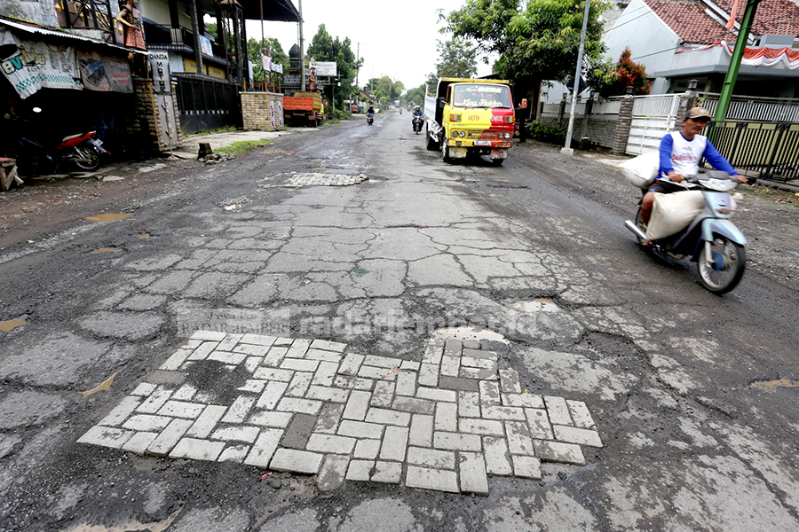 KREATIF: Inilah cara jitu mengatasi jalan berlubang di Jalan Yos Sudarso. Jalan lingkar yang melintasi Kelurahan Kranjingan tersebut ditambal dengan paving.