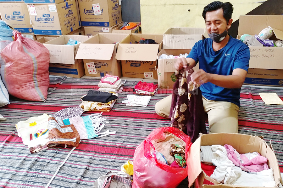 KELEBIHAN: Cak Oyong memilih pakaian bekas dari donasi warga ke korban banjir Gladak Kembar. Pakaian ini nantinya bakal dikelola oleh Bank Klambi Sobung Sarka.
