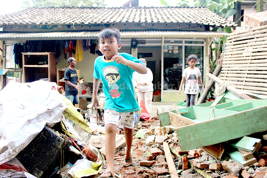 TETAP BERMAIN: Salah seorang anak kecil tampak berlarian di reruntuhan bangunan bekas banjir luapan Sungai Bedadung, belum lama ini.