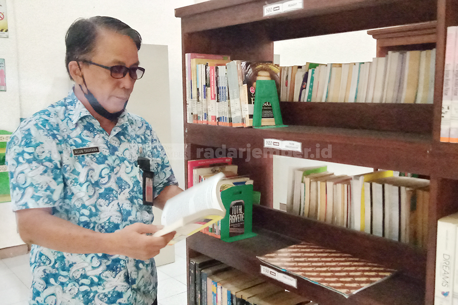 PERIKSA BUKU: Alun Taufana Sulistiyadi, Kepala Dinas Perpustakaan dan Kearsipan Bondowoso, saat mengecek buku di perpusda, kemarin.