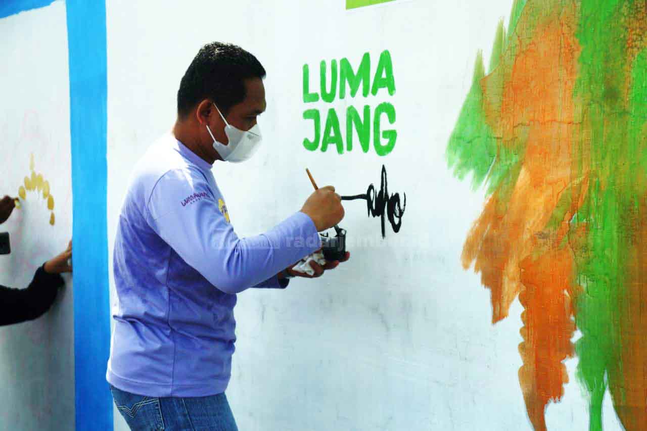 LUKIS RAME-RAME: Bupati Lumajang Thoriqul Haq saat melukis dinding tembok di eks lokalisasi Dolog atau yang sekarang terkenal dengan Kampung Anggur. Harapannya, pelan-pelan stigma masyarakat bisa terkikis.