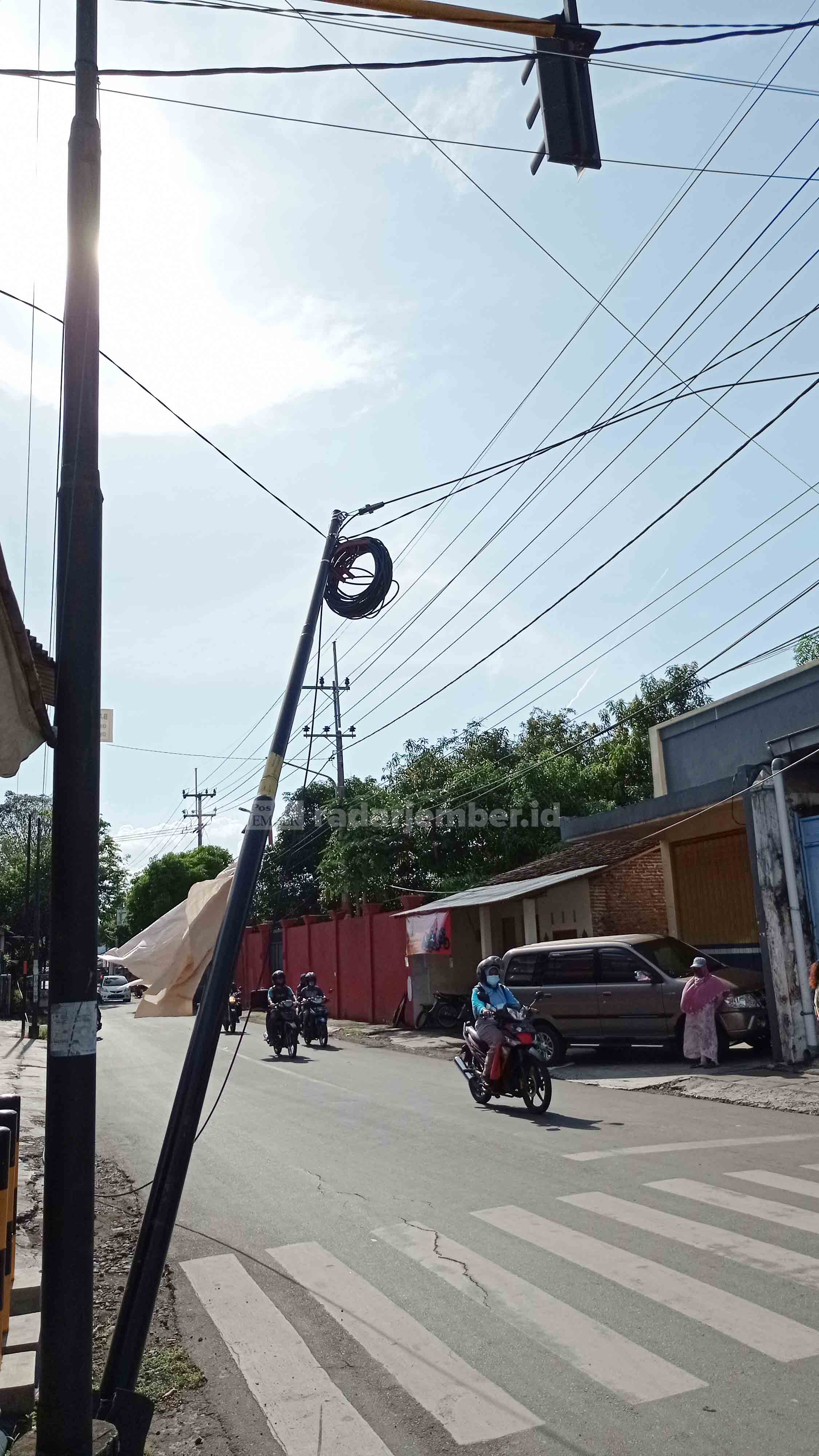 TERTAHAN: Tiang kabel milik salah satu provider nyaris roboh dan tertahan kabel di simpang lima Tompokersan, kemarin. Hal tersebut sudah dilaporkan warga, tapi belum ada tindakan.