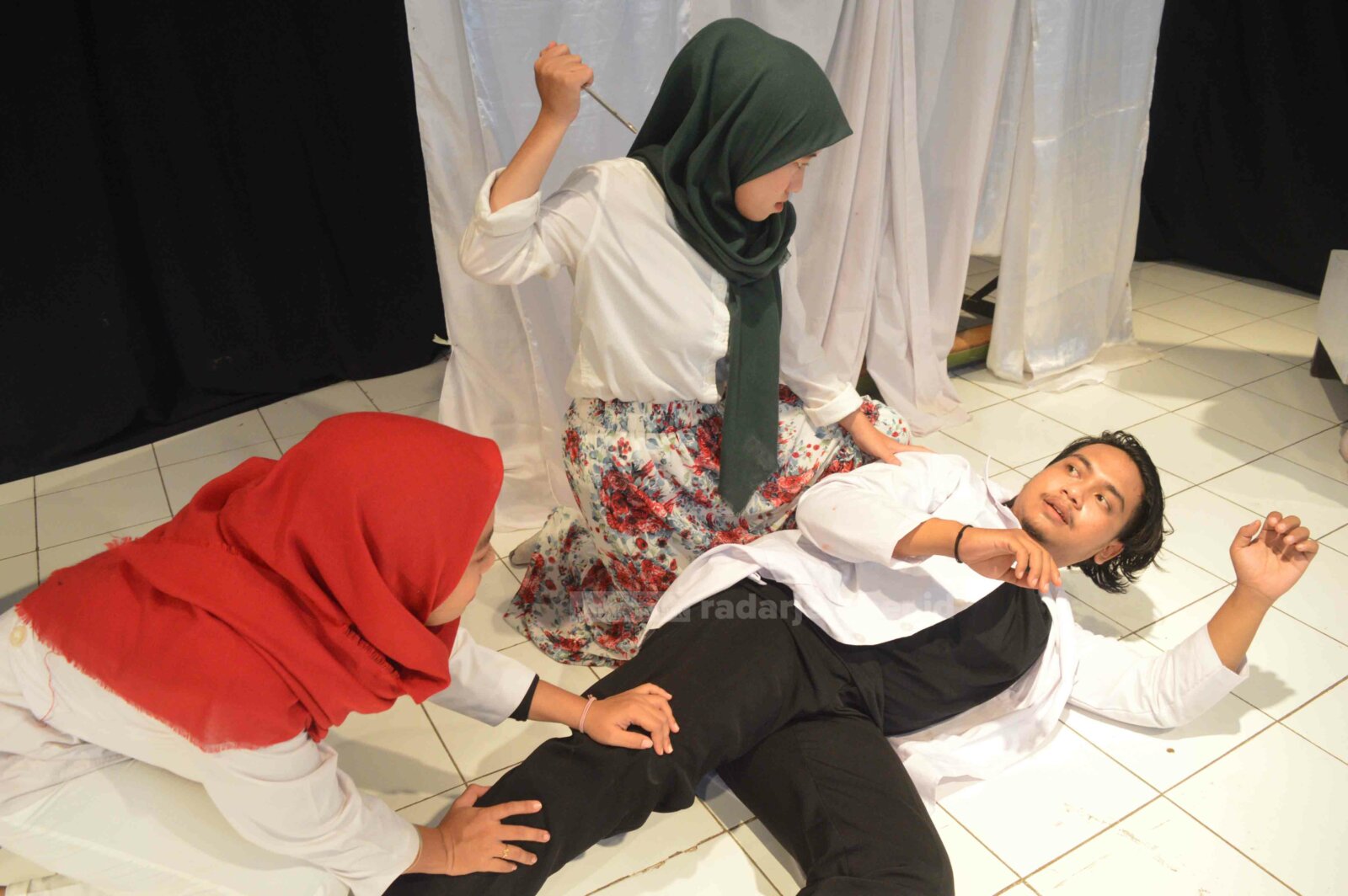REKAYASA PANGGUNG: Salah seorang aktor tersungkur, sedangkan dua pemeran lain berupaya membunuhnya. Drama yang dipentaskan di Gedung Graha Insani, Jalan Mastrip, Sumbersari, Minggu (25/4) malam itu, mengisahkan tentang gaya kepemimpinan di rezim Orba. 
