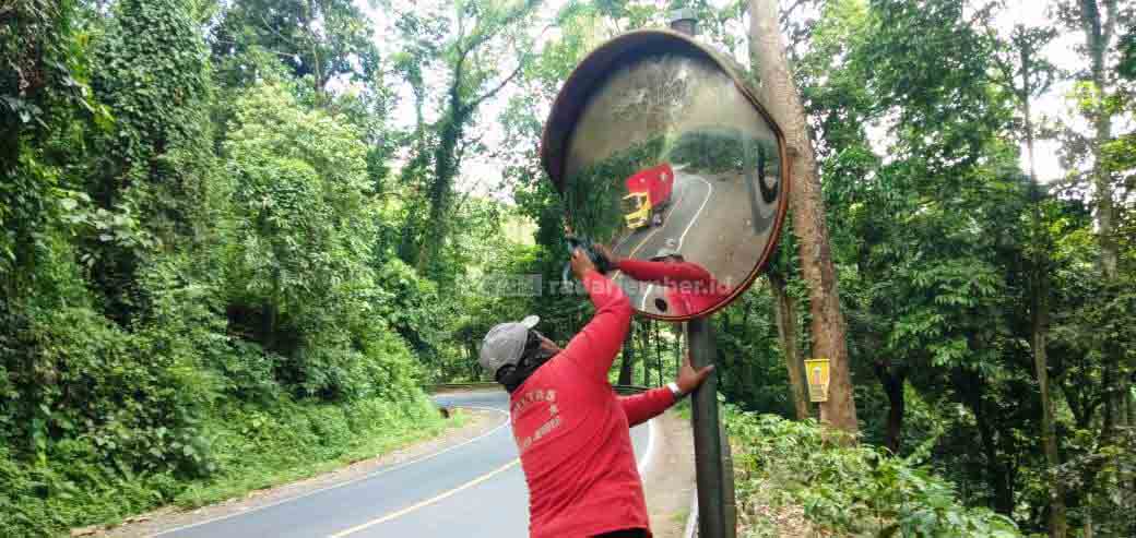 INISIATIF SENDIRI: Salah satu warga Desa Sidomulyo, Kecamatan Silo, membersihkan cermin cembung di Jalur Gumitir.