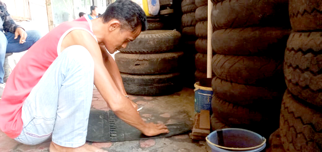 TELITI: Seorang perajin karet ban bekas sedang mengukur karet ban bekas untuk dibuat kerajinan.