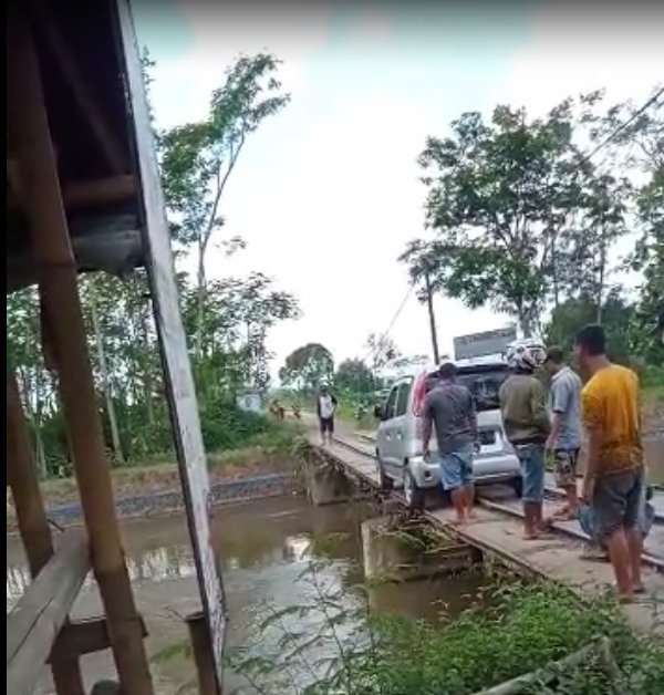 HAMPIR: Sejumlah masyarakat membantu mengevakuasi mobil yang hampir masuk sungai. Pengemudi kurang waspada sehingga roda mobil tergelincir saat menyeberangi jembatan rel di Dusun Pondokrejo, Kaliboto Kidul, akhir pekan lalu.