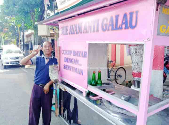 KREATIF: Seorang penjual mi ayam di Bondowoso saat menunjukan rombong jualannya yang dilengkapi julukan unik.