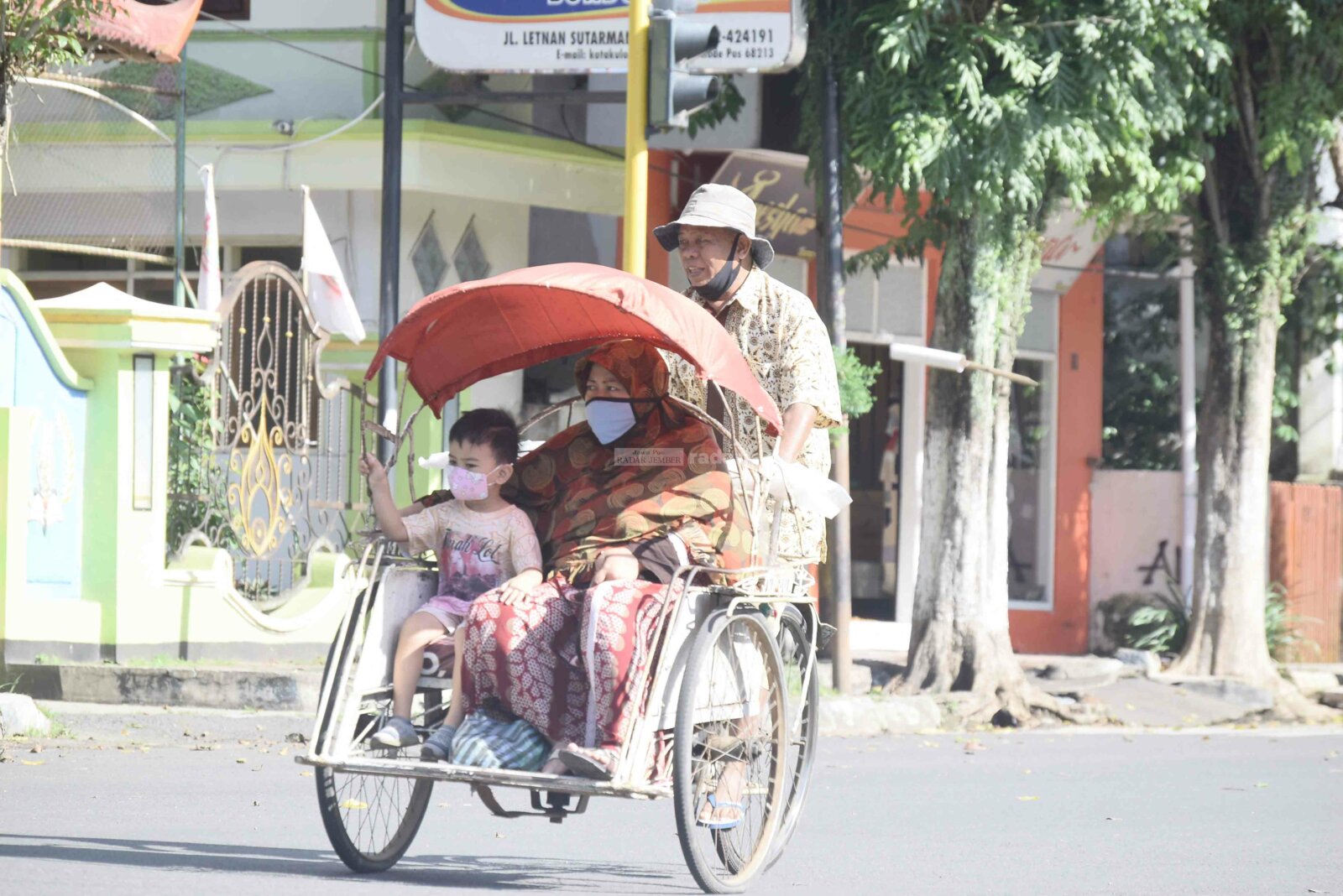 SAYANG ANAK: Salah satu orang tua dengan sang anak menaiki becak di kawasan alun-alun. Di tengah panas teriknya matahari, mereka naik becak agar lebih cepat sampai tujuan. Ratusan anak di Bondowoso pun harus kehilangan orang tuanya lantaran terpapar Covid