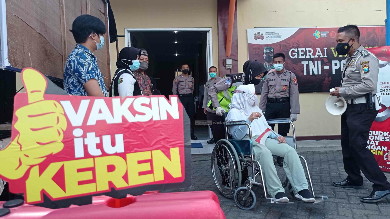 HUMANIS: Anggota Polres Lumajang mendorong kursi roda salah satu penyandang disabilitas di lokasi vaksinasi Satpas Polres Lumajang. Puluhan disabilitas di Lumajang menerima suntikan vaksinasi, kemarin.