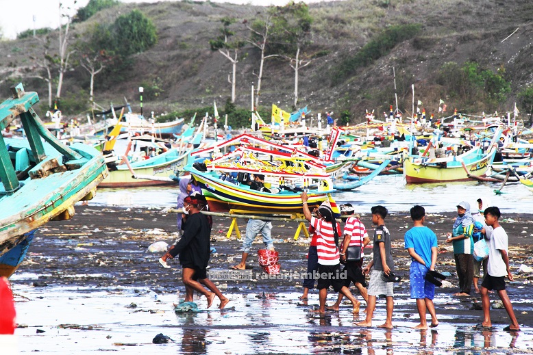 BERLANGSUNG SEDERHANA: Para nelayan membawa replika perahu untuk dilepas di tengah laut dalam acara petik laut di Desa Puger Kulon, Kecamatan Puger, kemarin (24/8)