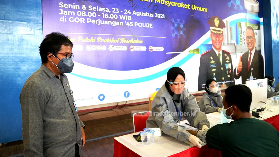 MENUJU HERD IMMUNITY: Wadir 1 Polije Abi Bakri meninjau vaksinasi yang digelar di GOR 45 Polije, kemarin (23/8). Mahasiswa juga terjun sebagai relawan dalam vaksinasi yang bekerja sama dengan Kodim 0824 Jember itu.