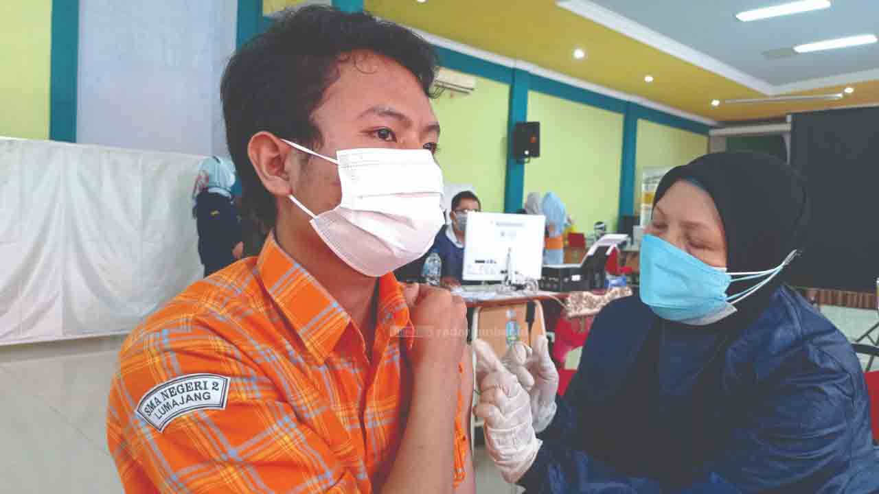 PERTAMA: Salah satu siswa SMAN 2 Lumajang menerima suntikan Vaksin Sinovac di gedung Pinandhita Hall, kemarin. SMAN 2 merupakan sekolah pertama yang dipilih untuk melaksanakan vaksinasi pelajar di Lumajang.